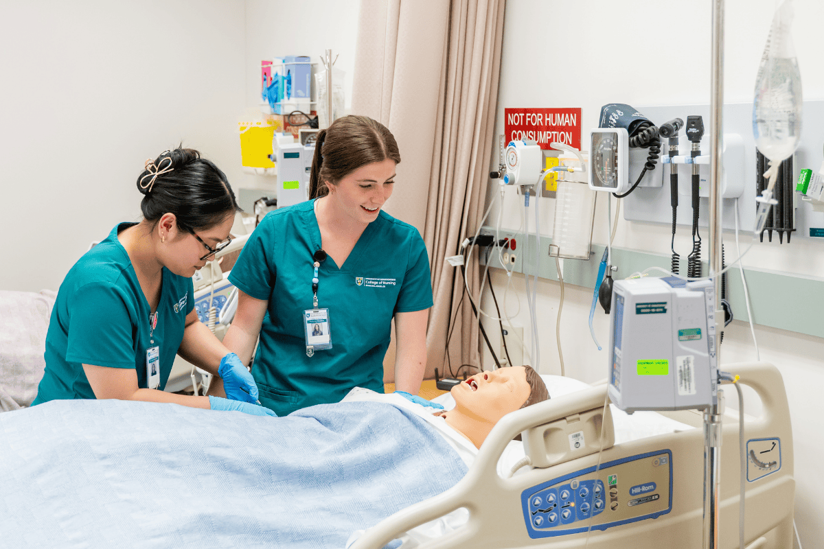 two female students working on a simulated patient in a hospital bed