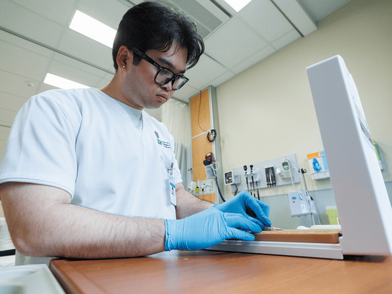 male nursing student practicing needle insertion in the lab