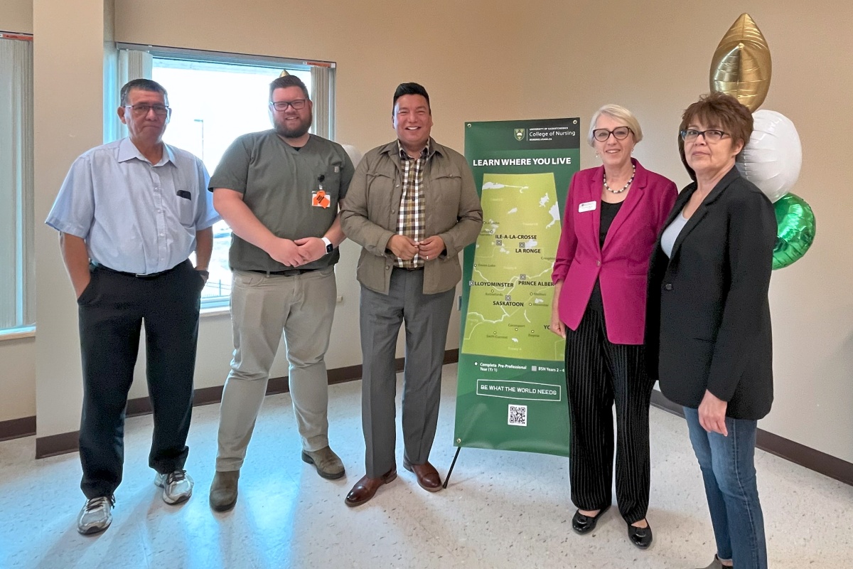 three men and one woman are joined by Dean Solina Richter standing beside a Learn Where You Live banner, smiling for a photo
