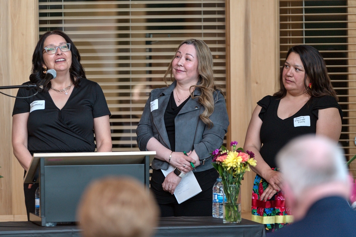 Three female alumni standing at a podium.