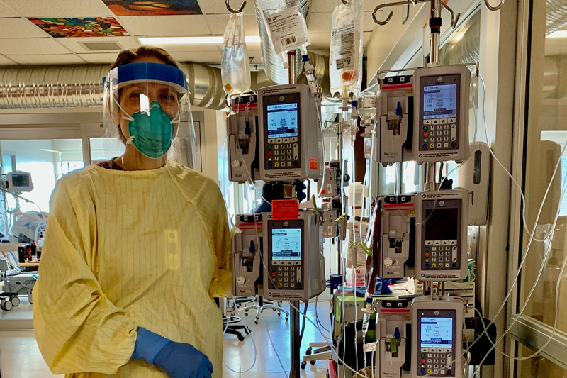 Kathy Pickerl wearing personal protective equipment, standing beside monitors in the hospital.