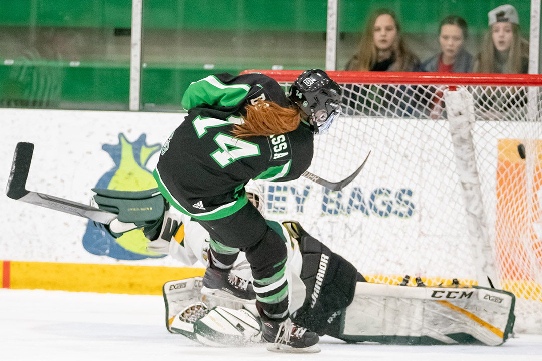 Female hockey player shooting a hockey puck into a net