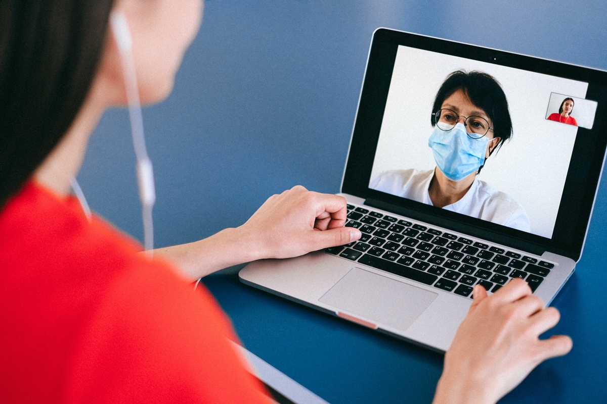 Woman speaking to a person with a mask on via the computer
