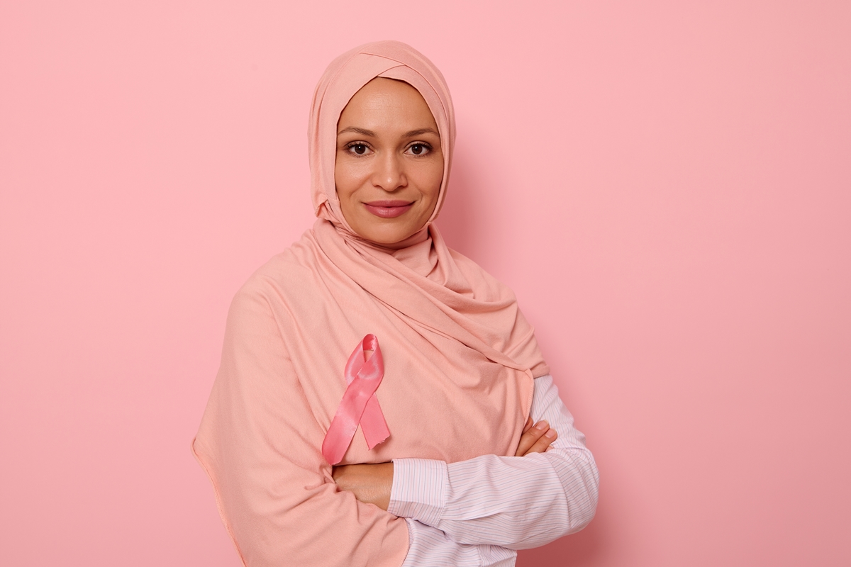 Woman with a pink head covering and a pink ribbon on her chest