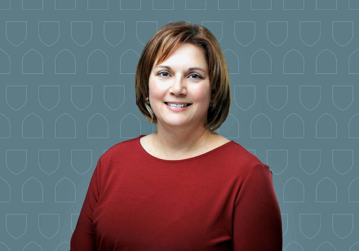 Dr. Tania Kristoff sitting and smiling at the camera with a grey background 