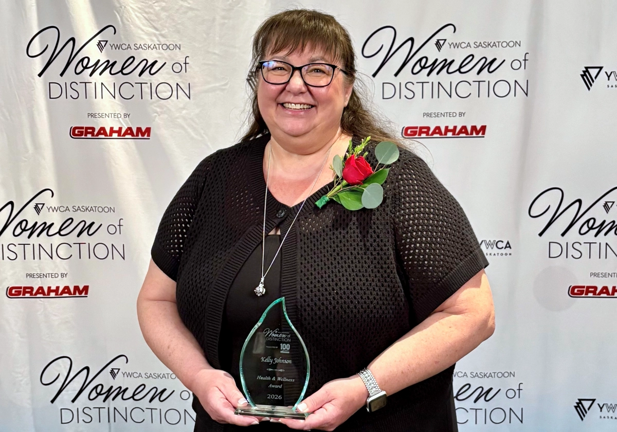 Kelly Johnson smiling, holding her trophy from the 2026 YWCA Women of Distinction awards ceremony