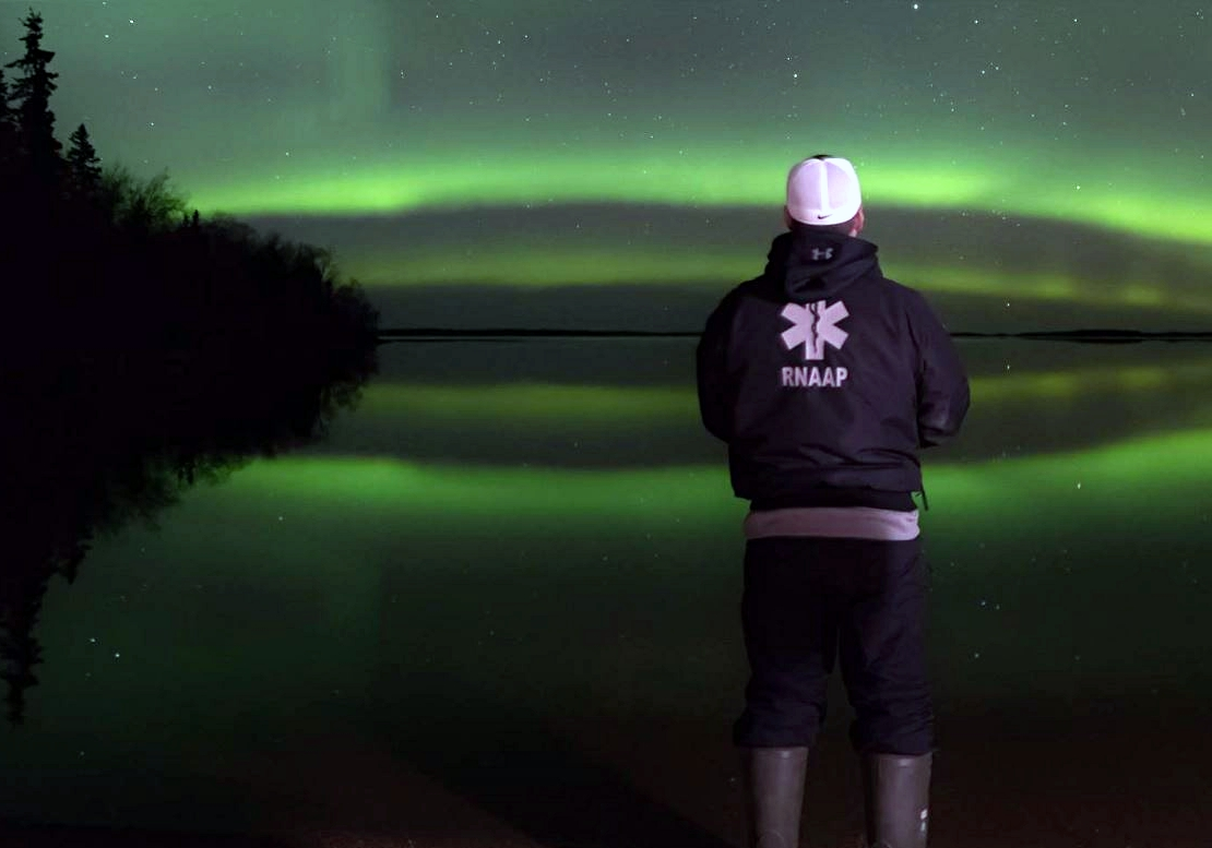 Dre Erwin standing in front of northern lights.
